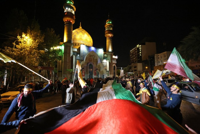 Des manifestants brandissent le drapeau iranien et des drapeaux palestiniens alors qu'ils se rassemblent sur la place de la Palestine à Téhéran.