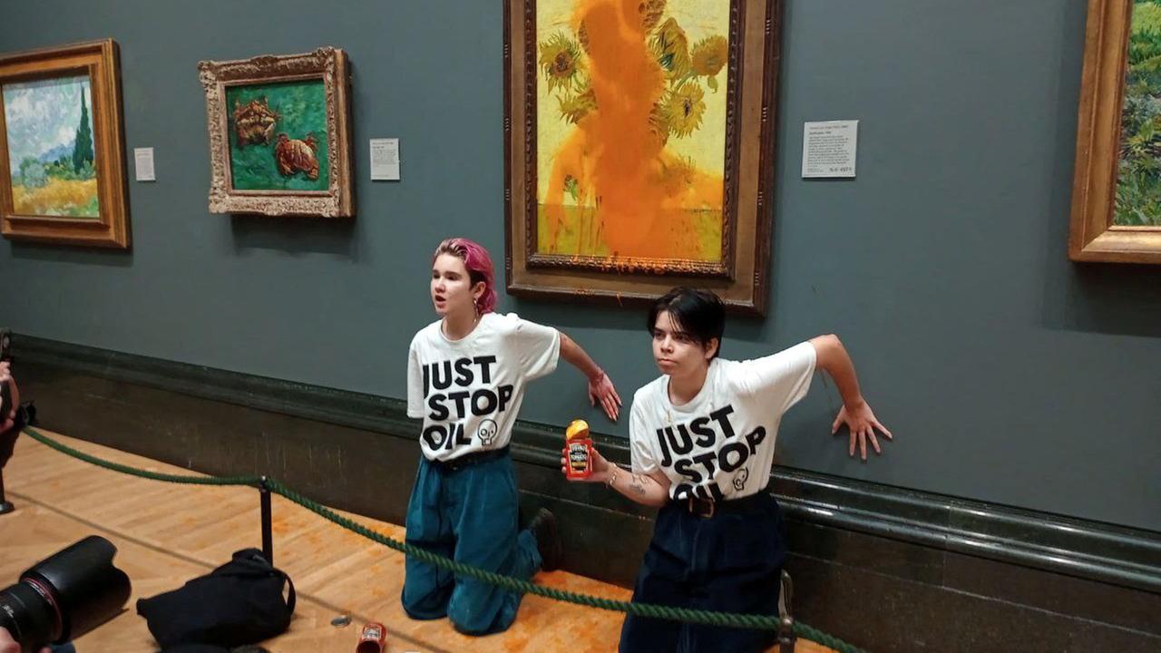 Des militants de "Arrêtez simplement le pétrole" Coller leurs mains au mur après avoir jeté de la soupe sur un tableau de Van Gogh "Tournesols" à la National Gallery de Londres