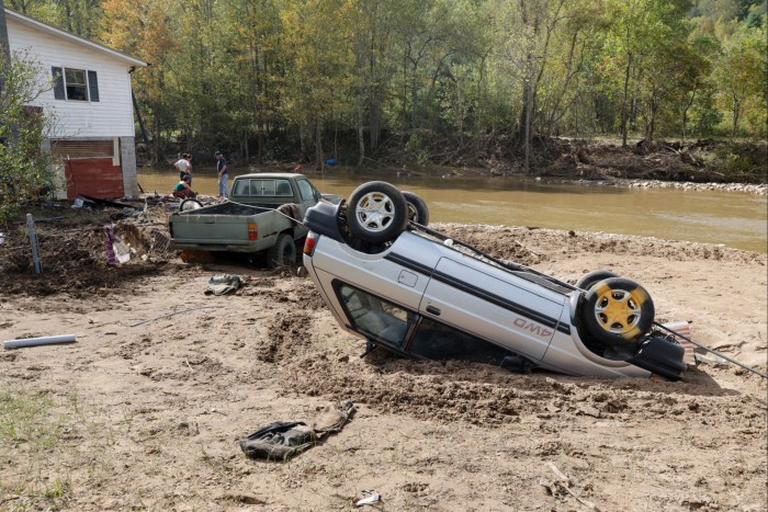 Une voiture renversée repose dans la boue près d'un ruisseau inondé à Barnardsville, en Caroline du Nord