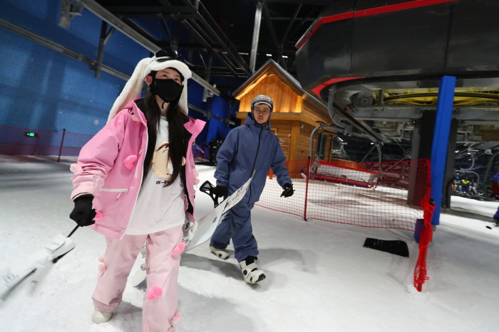 Un homme et une femme en combinaison de ski entrent dans une arène couverte