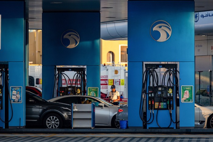 Un travailleur fait le plein de véhicules sur le parvis d'une station-service Adnoc dans le district de Jumeirah à Duba