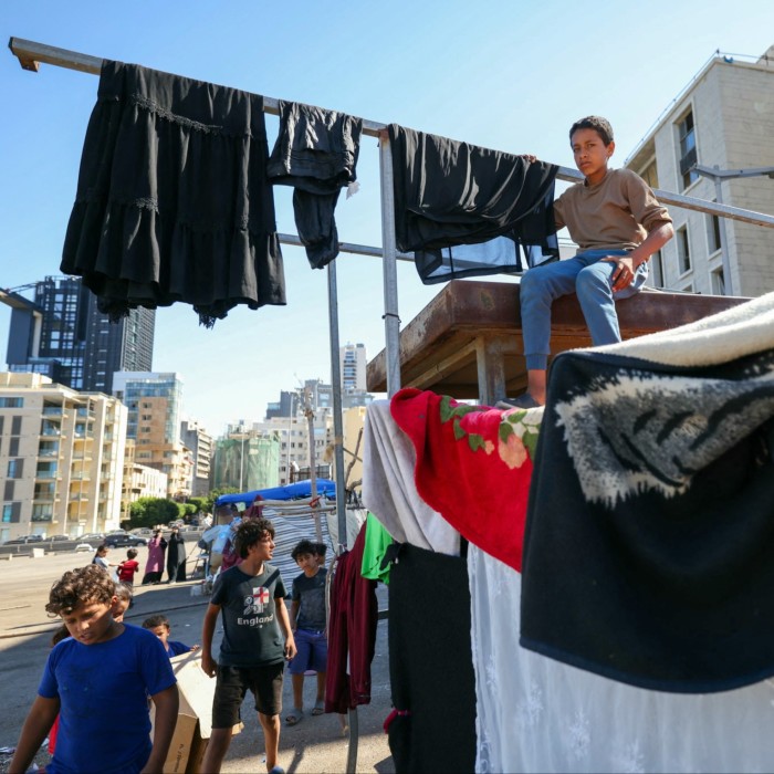 Des enfants déplacés sont photographiés à côté d'abris de fortune sur un parking du centre de Beyrouth.