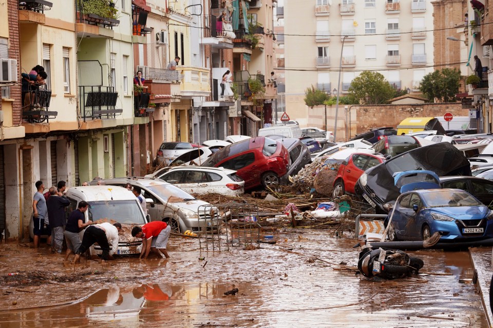 Les habitants regardent aujourd'hui les voitures entassées après avoir été emportées par les inondations à Valence