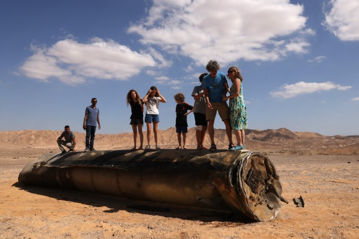 Les gens se tiennent debout sur les restes d'un missile