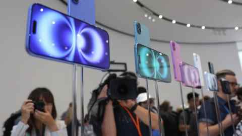 Les nouveaux modèles d'iPhone 16 Pro Max sont exposés sur des stands. En arrière-plan, les participants, notamment des photographes et des vidéastes, capturent des images et des séquences des appareils.