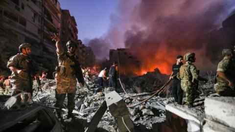 Des soldats de l'armée libanaise se rassemblent sur les décombres d'immeubles rasés alors que les gens fuient les flammes, suite aux frappes aériennes israéliennes dans le quartier Haret Hreik de la banlieue sud de Beyrouth