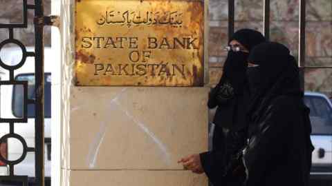 Des femmes passent devant la Banque d'État du Pakistan à Karachi