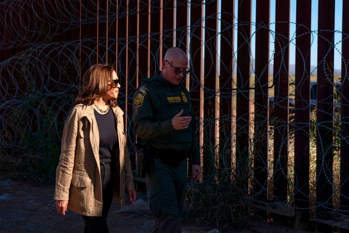 Kamala Harris marche aux côtés d'un responsable de la patrouille frontalière américaine près de la barrière frontalière américano-mexicaine surmontée de barbelés à Douglas, en Arizona.