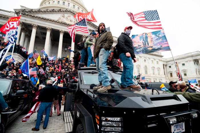 Les partisans de Trump se tiennent sur le véhicule blindé de la police du Capitole des États-Unis tandis que d'autres envahissent les marches du Capitole, le 6 janvier 2021.