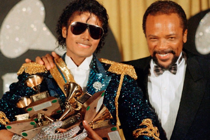 Michael Jackson, vêtu d'une veste à sequins et de lunettes de soleil, détient huit Grammy Awards en posant avec Quincy Jones, souriant et vêtu d'un smoking, lors des Grammy Awards à Los Angeles le 28 février 1984.