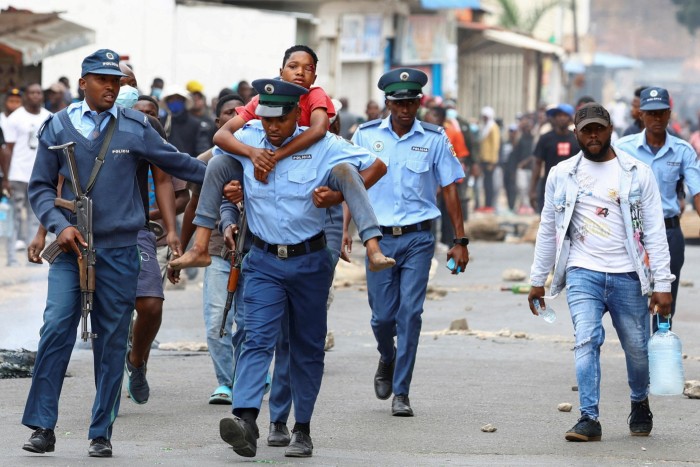 Un policier transporte une personne blessée lors d'une « fermeture nationale » contre le résultat des élections, dans la commune de Luis Cabral à Maputo, au Mozambique