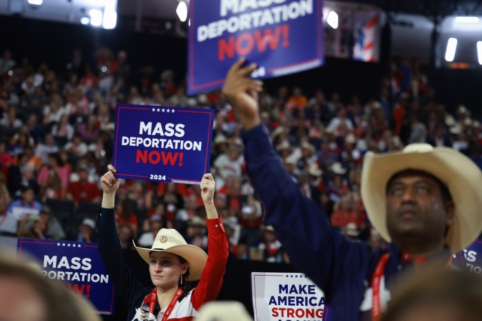 Des personnes portant des chapeaux de cowboy se tiennent dans une foule brandissant des pancartes indiquant « expulsion massive maintenant »