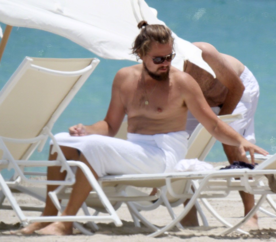 Léo arborant un nouveau look avec cheveux longs et barbe, torse nu sur une plage de Miami