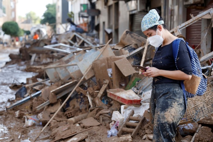 Une femme regarde son téléphone portable, entourée de débris