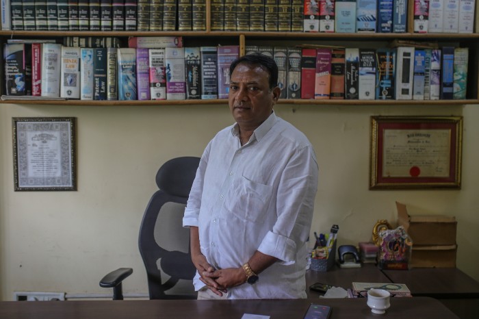 Raju Korde pose devant des rangées de livres