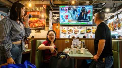 Les gens regardent les résultats préliminaires des élections américaines sur un écran de télévision dans un restaurant à Hong Kong