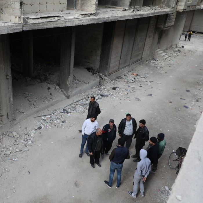 Des hommes se tiennent au milieu de bâtiments en ruine à Tadamon