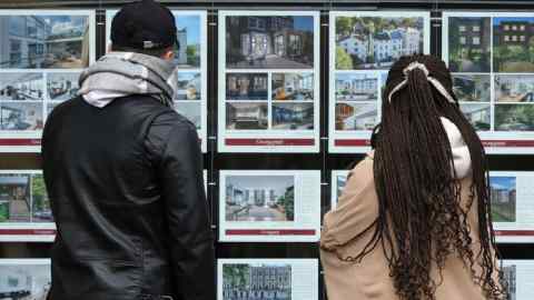 Deux personnes regardant par la fenêtre d'un agent immobilier