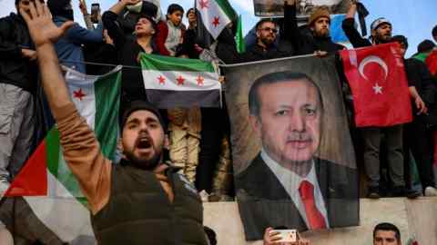 Des membres de la communauté syrienne d'Istanbul brandissent une bannière du président turc Recep Tayyip Erdoğan alors qu'ils célèbrent la chute du président syrien Bashar al-Assad