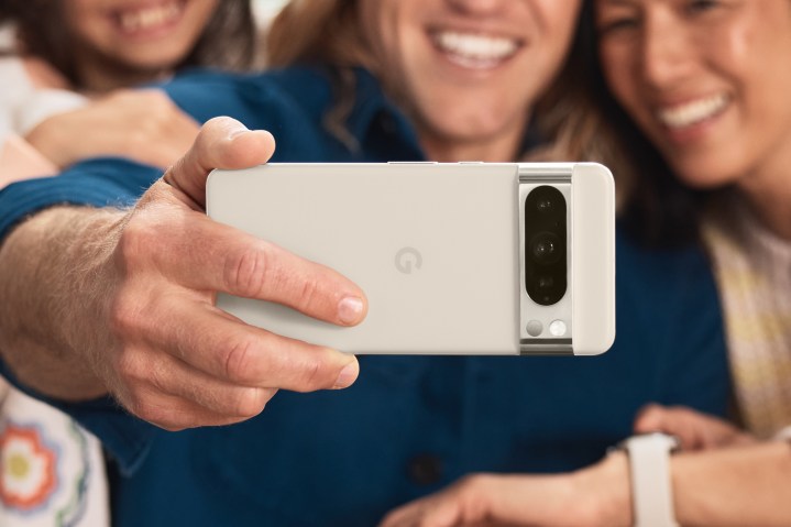 Grup selfiesi çekmek için beyaz bir Google Pixel 8 Pro tutan biri.