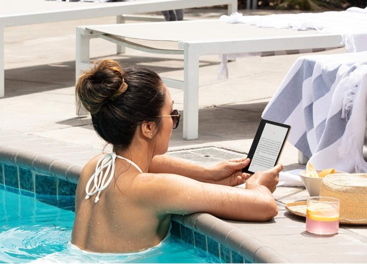 Yüzme havuzunda Amazon Kindle Oasis'te e-kitap okuyan bir kadın.