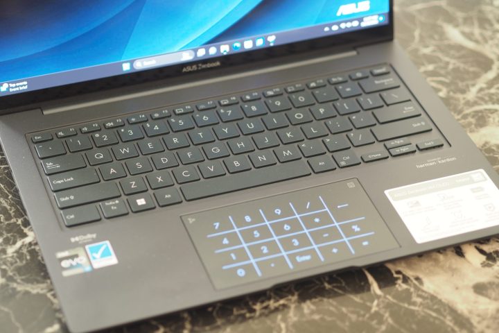 Asus Zenbook 14X OLED'in klavyeyi ve LED dokunmatik yüzeyi gösteren yukarıdan aşağıya görünümü.