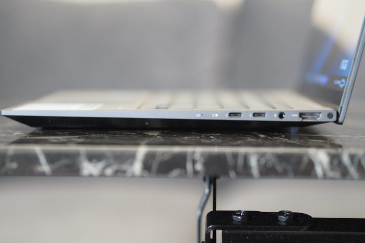 Asus Zenbook 14X OLED'in bağlantı noktalarını ve kapağını gösteren yandan görünümü.