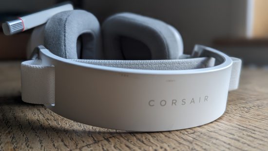 Corsair HS80 Max incelemesi: Geri çekilmiş mikrofonlu beyaz bir kulaklık, ahşap bir masanın üzerinde yukarıdan görünüyor.