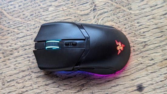 Razer Cobra Pro incelemesi: Ahşap bir yüzey üzerinde çok renkli RGB'ye sahip siyah bir fare görünüyor.