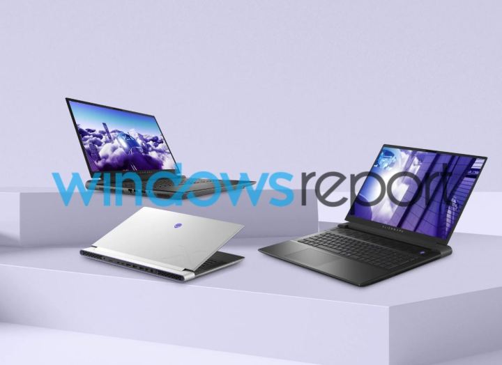 Gri bir arka planın önünde, masanın üzerinde üç yeni Alienware dizüstü bilgisayar.
