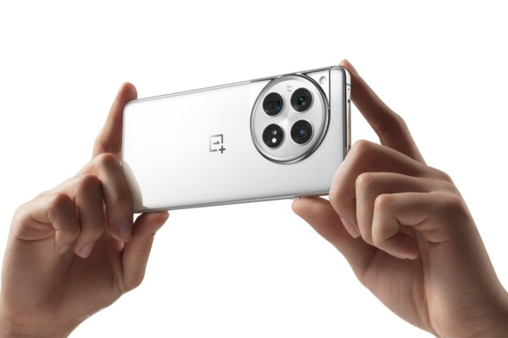 Beyaz/gümüş OnePlus 12'yi tutan birinin fotoğrafı.