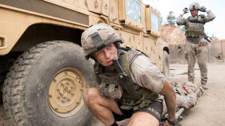 Bir ABD askeri askeri bir aracın arkasında çömeliyor.