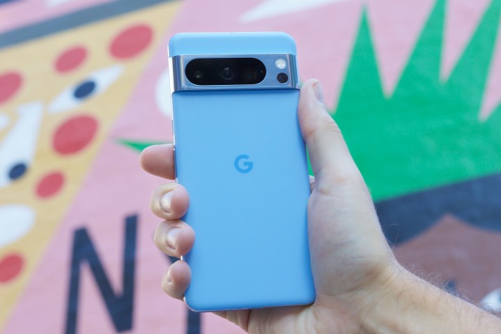 Renkli bir arka planın önünde Google Pixel 8 Pro'yu tutan biri.