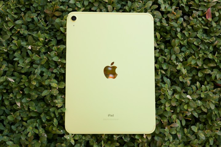 Yeşil bir çalının üzerinde yüzüstü duran sarı iPad (2022).