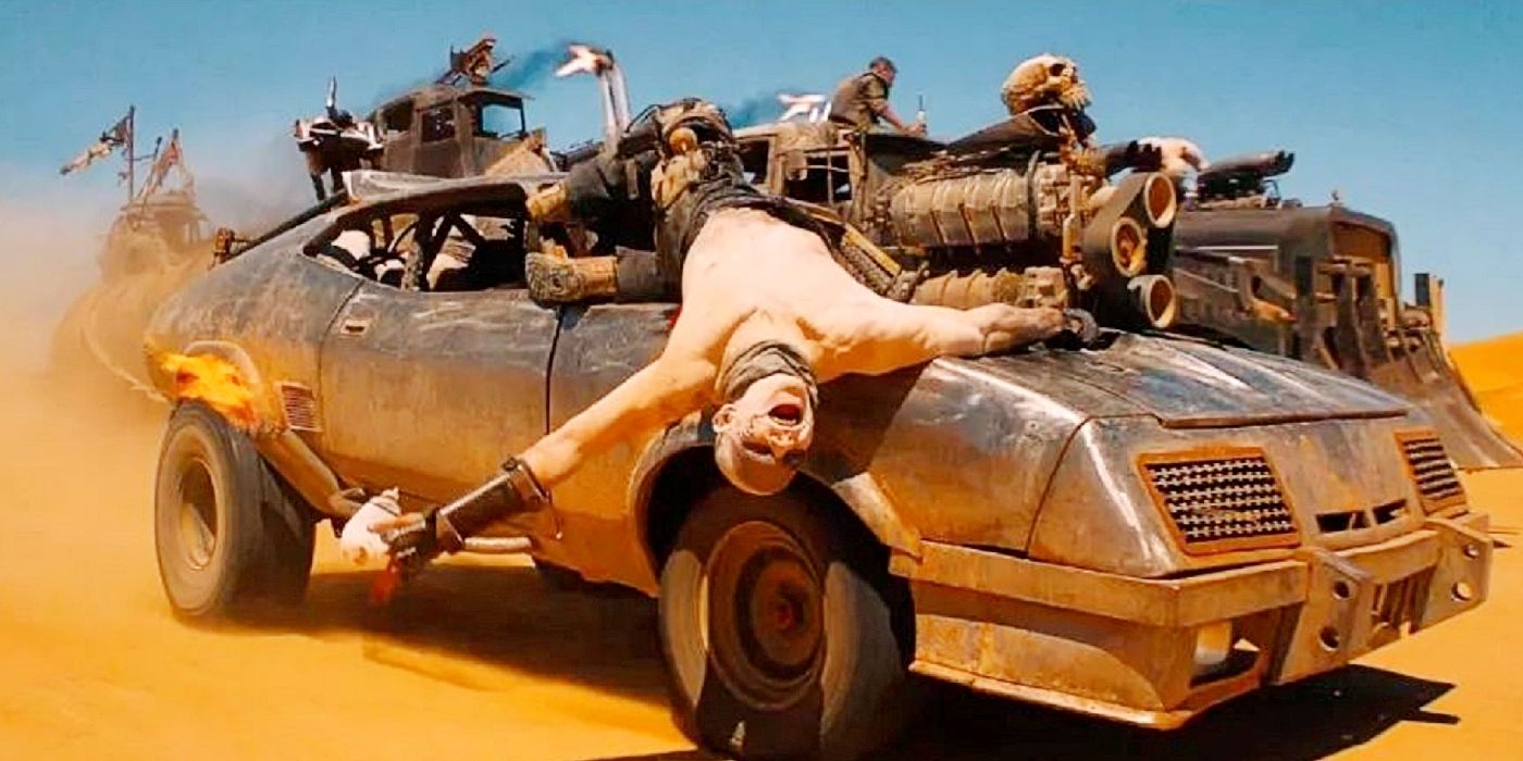Mad Max: Fury Road'da bir War Boy, hareket eden bir kaslı arabaya asılıyor.