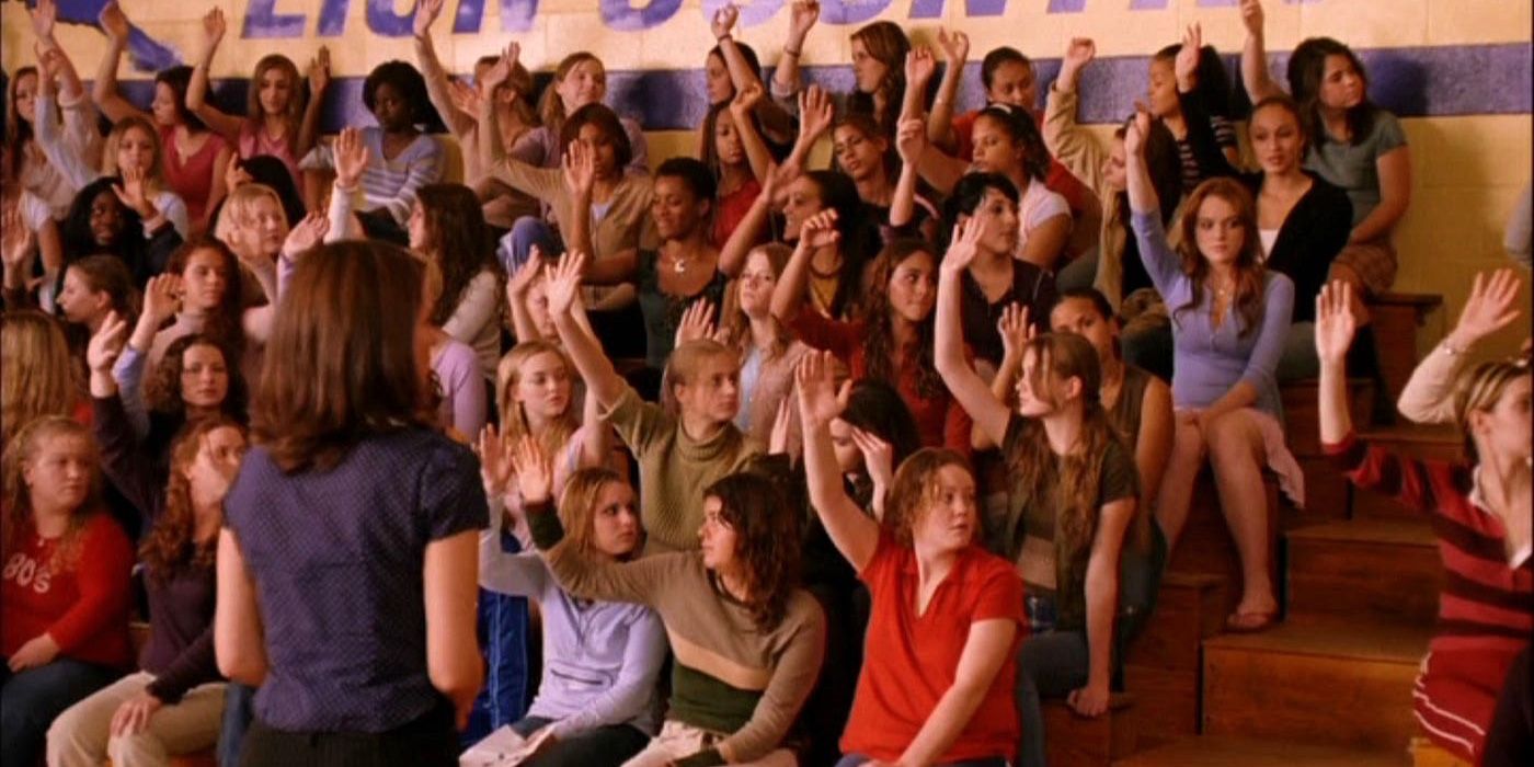 Mean Girls'te Bayan Norbury (Tina Fey) sorunlarına değinirken spor salonundaki kızlar ellerini kaldırıyor.