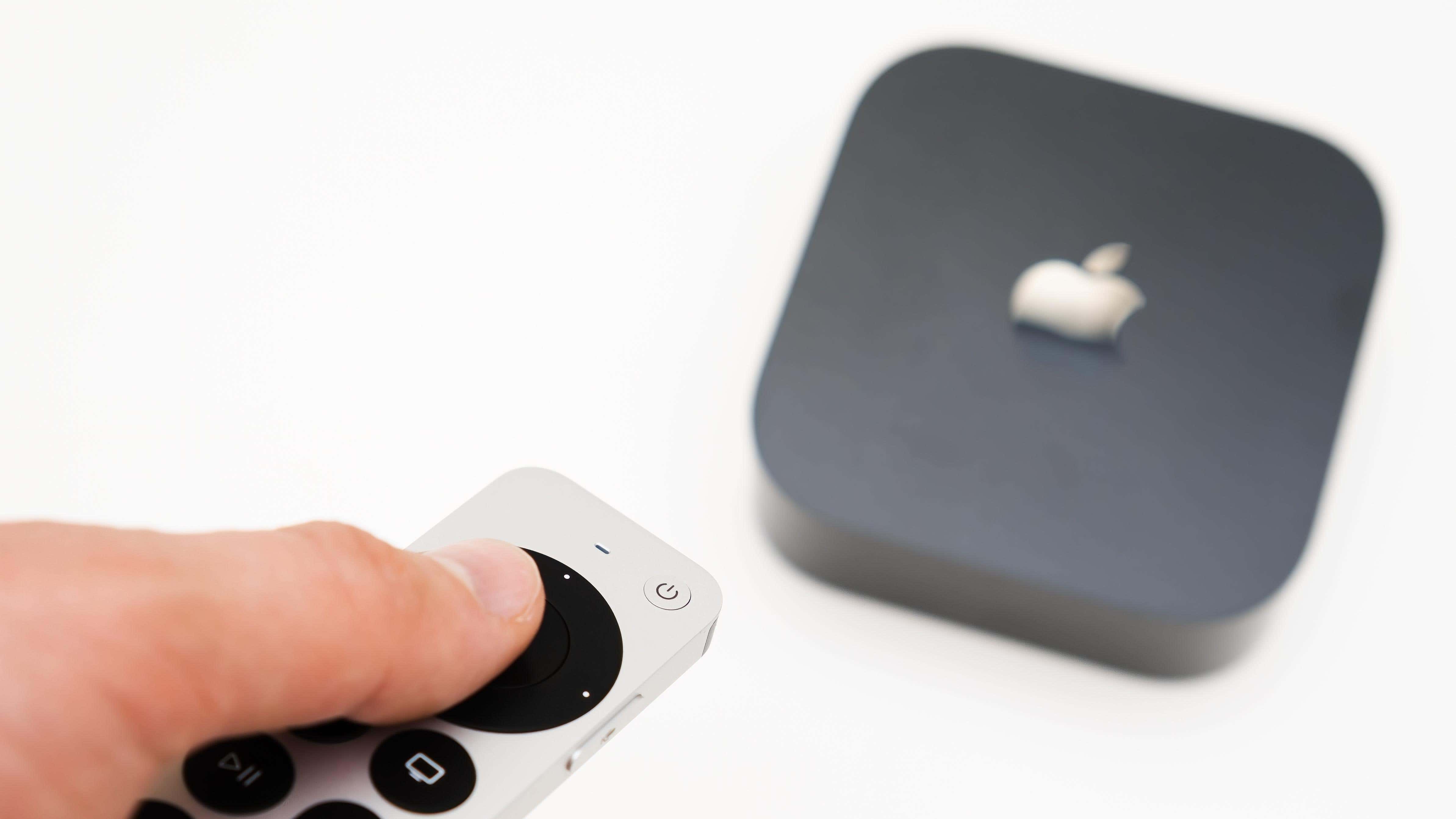 Adam eli uzaktan kumandayı kullanarak yeni siyah Apple TV 4K medya akışını açıyor