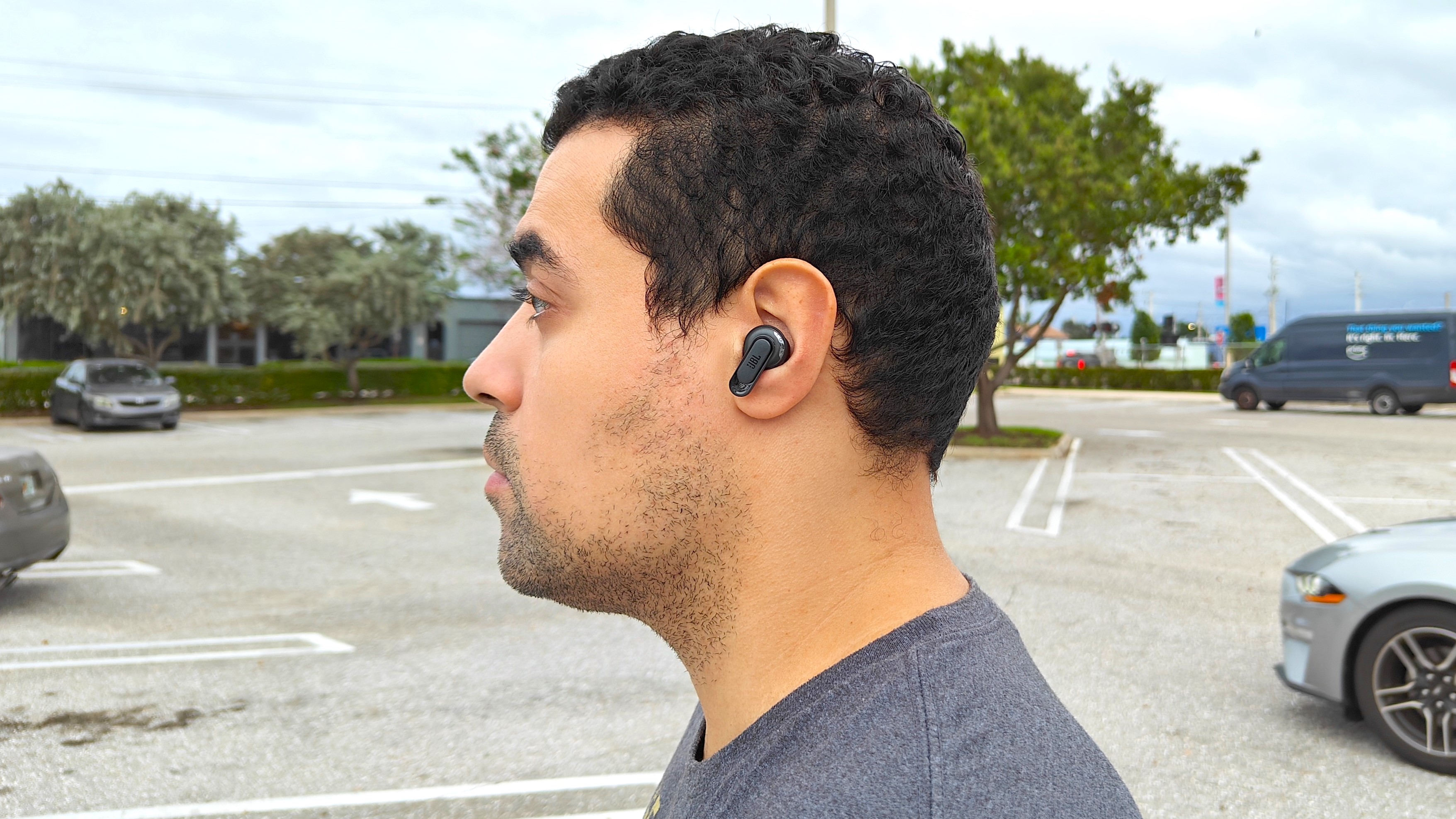JBL Tour Pro 2 kablosuz kulaklık takan incelemecinin yan profili