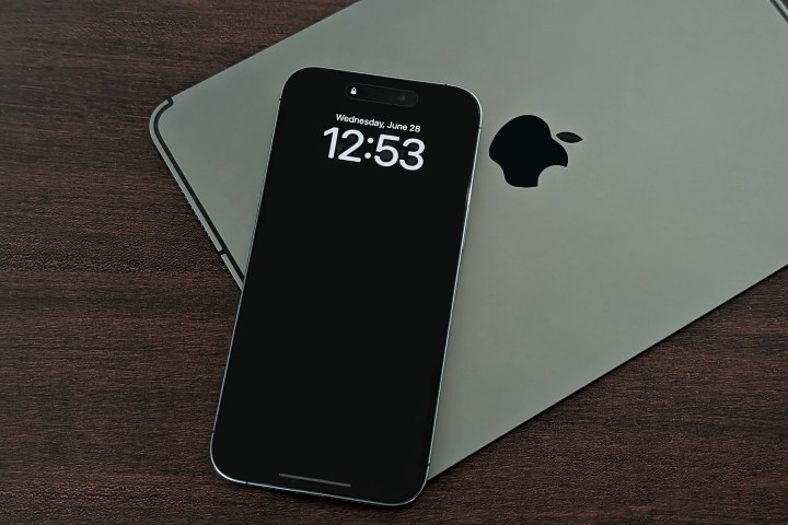 iPad'in üzerinde duran iPhone 14 Pro Max, duvar kağıdı ayarı kapalıyken ekranın her zaman açık olduğunu gösteriyor.