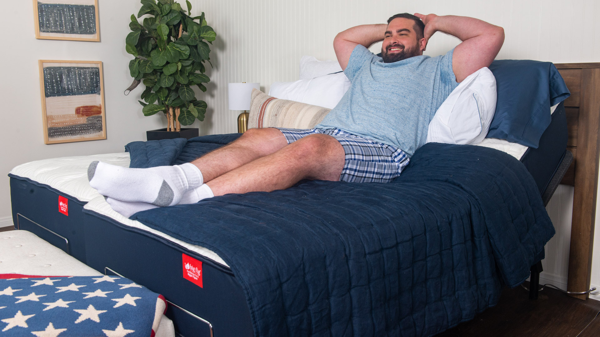 Mavi tişörtlü bir adam Big Fig hibrit yatağın üzerinde dinleniyor