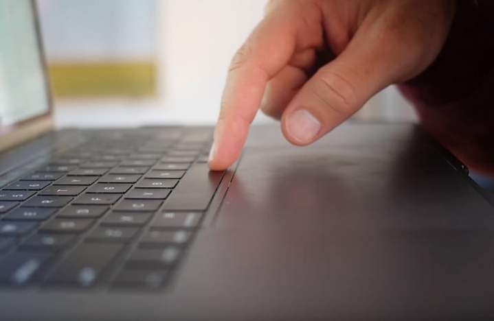 Apple MacBook Pro'nun klavyedeki parmağı gösteren yandan görünümü.