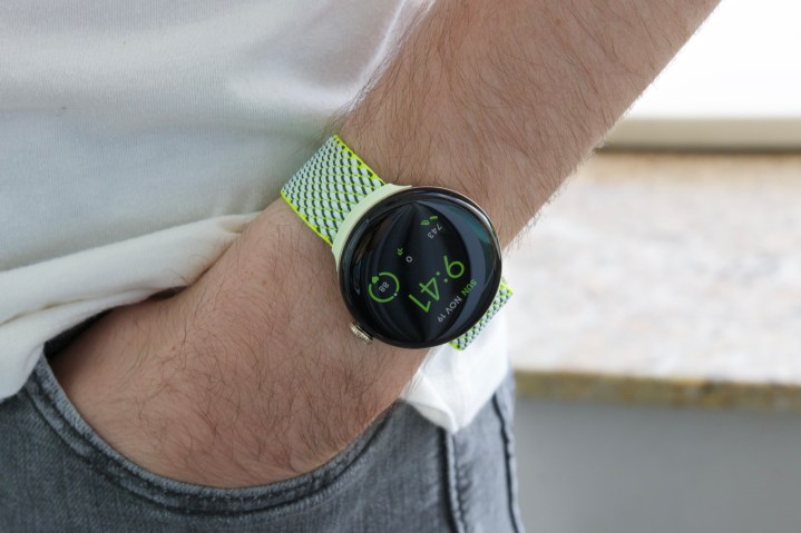 Sarı/yeşil kumaş bantlı Google Pixel Watch 2 takan biri.
