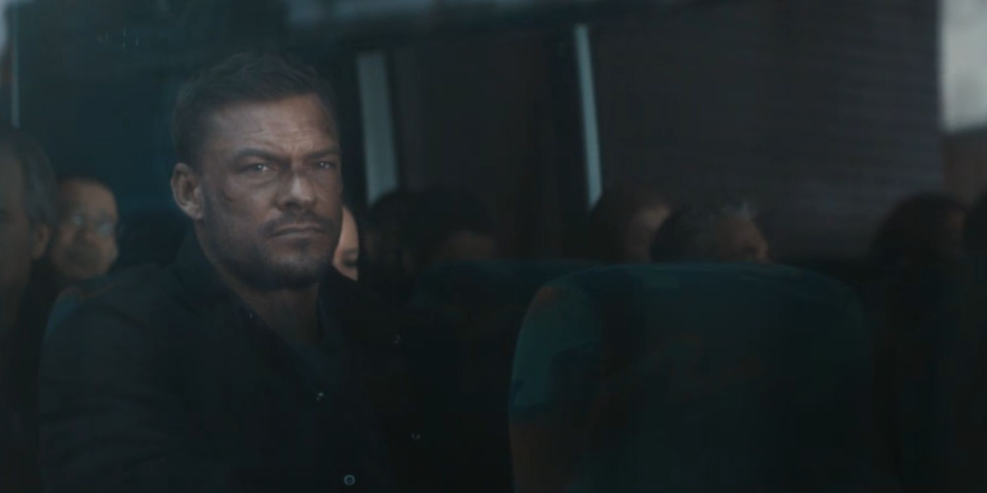 Alan Ritchson, otobüste oturan ve pencereden dışarı bakan Reacher rolünde