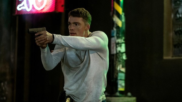 The Night Agent'tan bir sahnede beyaz kazaklı Peter elinde silahla görülüyor.