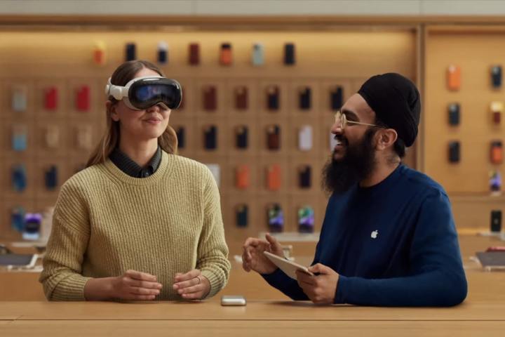 Bir Apple çalışanı, bir kişiye Apple Store'da Vision Pro kulaklığının nasıl kullanılacağını gösteriyor.
