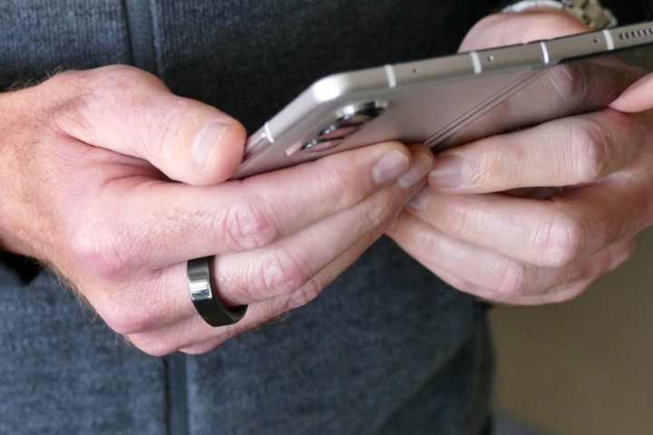 Bir adamın Galaxy Z Fold 3'ü tutarken parmağına taktığı Oura Yüzüğü.