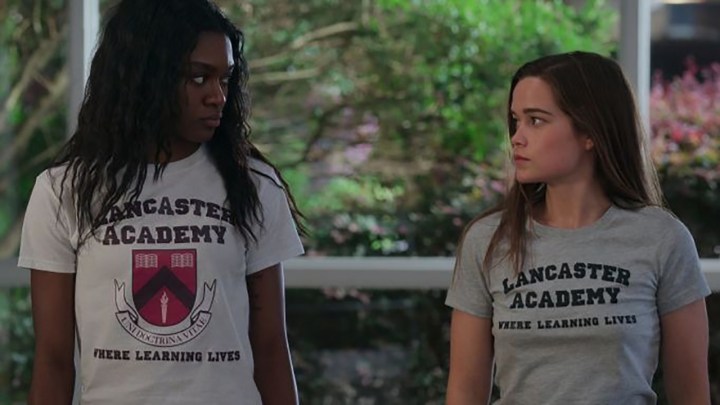 Netflix'teki First Kill filminden bir sahnede lise tişörtleri giyen iki genç kadın birbirlerine bakıyor.