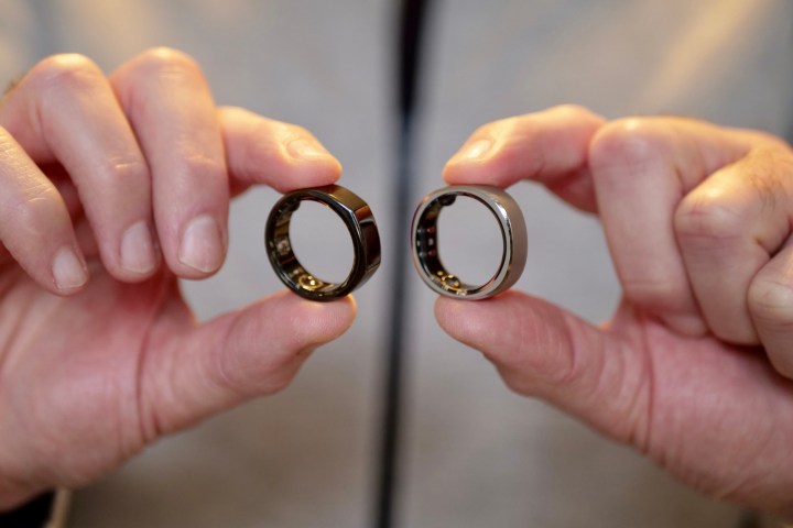 RingConn Akıllı Yüzüğünü ve Oura Yüzüğünü tutan bir kişi.