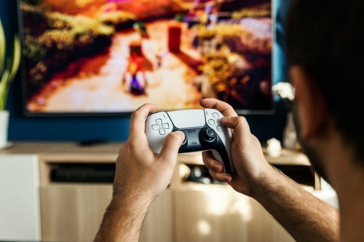 Bir kişi PS5 DualSense kumandasını kullanarak Crash Bandicoot oynuyor.