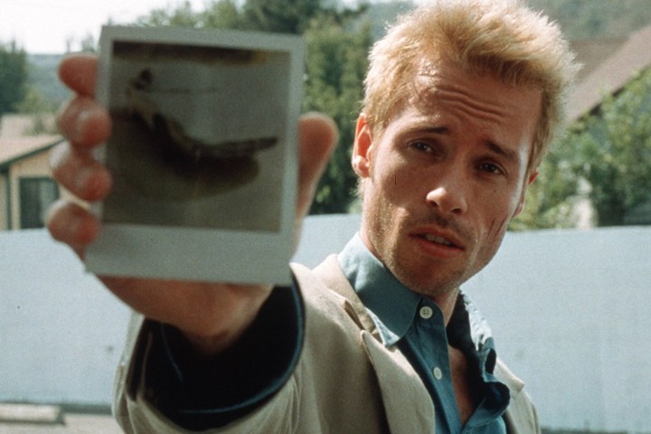Guy Pearce, Memento'da Leonard Shelby rolünde kameraya polaroid gösteriyor.